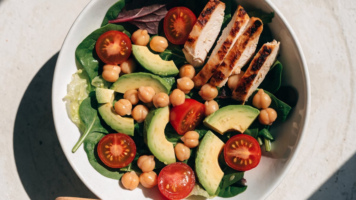 A colorful healthy salad bowl with greens, tomatoes and grilled chicken